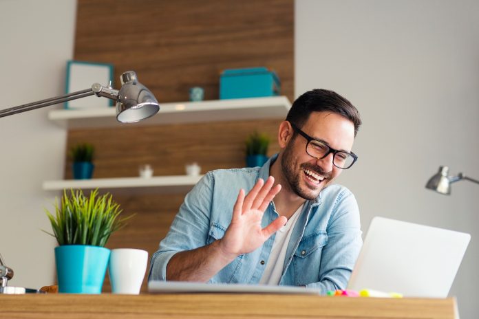 Smiling young man having video call and waving